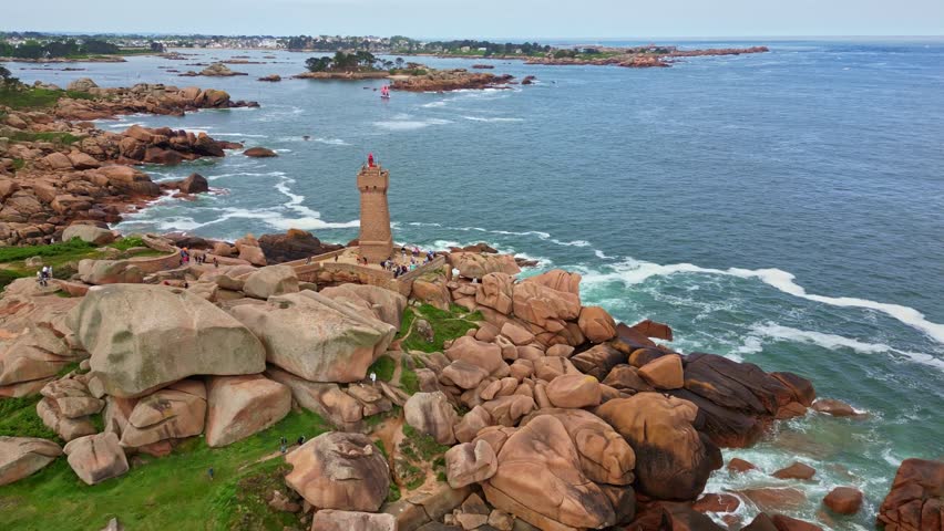 Mean Ruz lighthouse on Pink Granite Coast, tourists exploring coast of Ploumanac