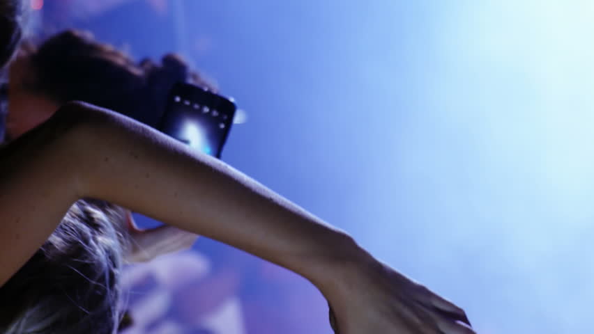 Animation of digital social media interface icons over woman making heart shape with her hands during concert at music venue. Global networking social media entertainment, concept digital composite. - Powered by Shutterstock - Get 15% off with code: PIKWIZARD15