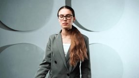 Young Caucasian businesswoman in formal attire dials a number on her smartphone brings it to her ear, and waits calmly for a response, her face serious and focused. Studio lighting, neutral background - Powered by Shutterstock - Get 15% off with code: PIKWIZARD15