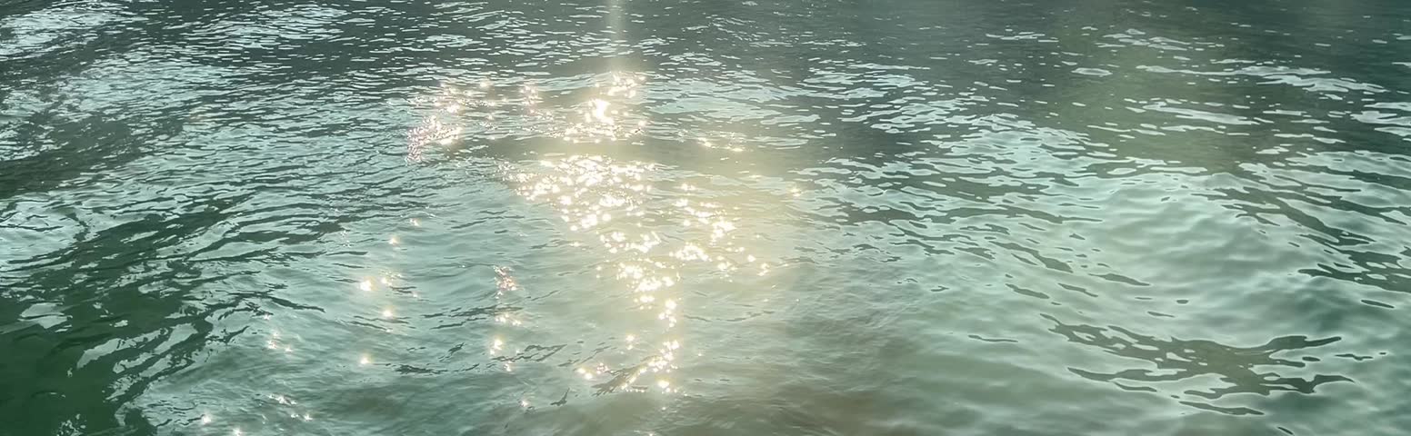 Sparkling Water Surface, capturing the dazzling effect of sunlight reflecting off gentle waves, creating a shimmering, sparkling water surface. 