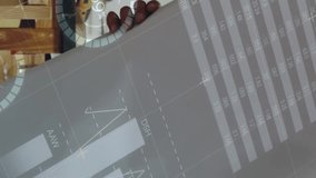 Digital composite of a Caucasian man looking at plans in his workshop with graphs and statistics running in the foreground 4k - Powered by Shutterstock - Get 15% off with code: PIKWIZARD15