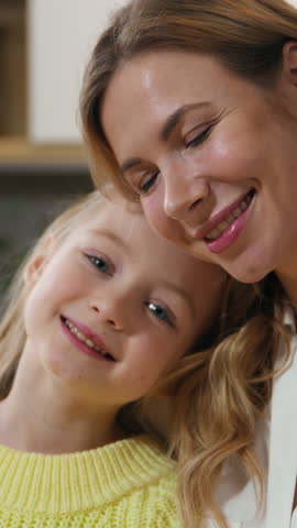 Happy family at kitchen portrait Caucasian preschool cute affectionate adopted little girl child daughter schoolgirl hugging cuddle care mother with closed eyes cuddling mum kid enjoy tender at home