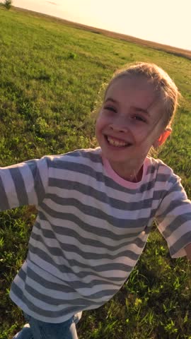 Girl kid holds her dad hand, daughter dad are spinning together on lawn. Happy family. Dad child girl playing on grass in park holding hands. Father kid daughter are having fun together in meadow POV