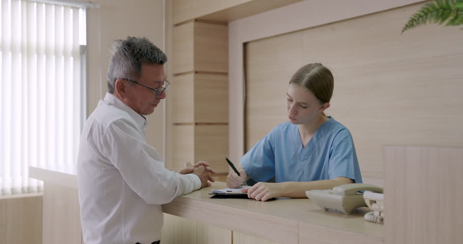 Slowmotion scene of hospital billing interaction with asian male preparing credit card payment while young female nurse handling medical charge process at reception counter