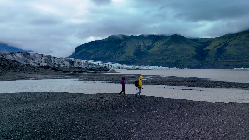 Adventurers stroll along the shoreline of Skaftafell Glacier, surrounded by breathtaking landscapes of Iceland