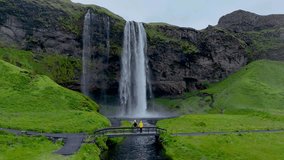 A couple stands on a bridge near the magnificent Seljalandsfoss waterfall in Iceland. - Powered by Shutterstock - Get 15% off with code: PIKWIZARD15