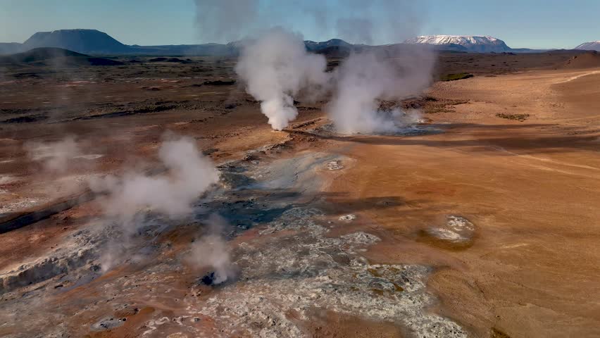 Witness the surreal landscape of Hverir in Iceland, where steam rises from boiling geothermal springs.