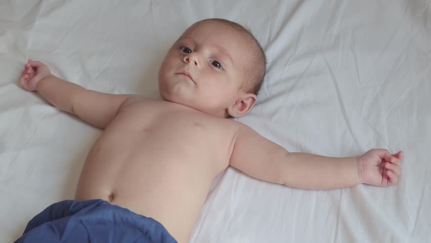 Baby lying on bed crying and having hiccups
