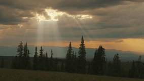 Sunrays Behind Clouds Across Mountain Trees. Time-lapse, Pan Right Shot - Powered by Shutterstock - Get 15% off with code: PIKWIZARD15