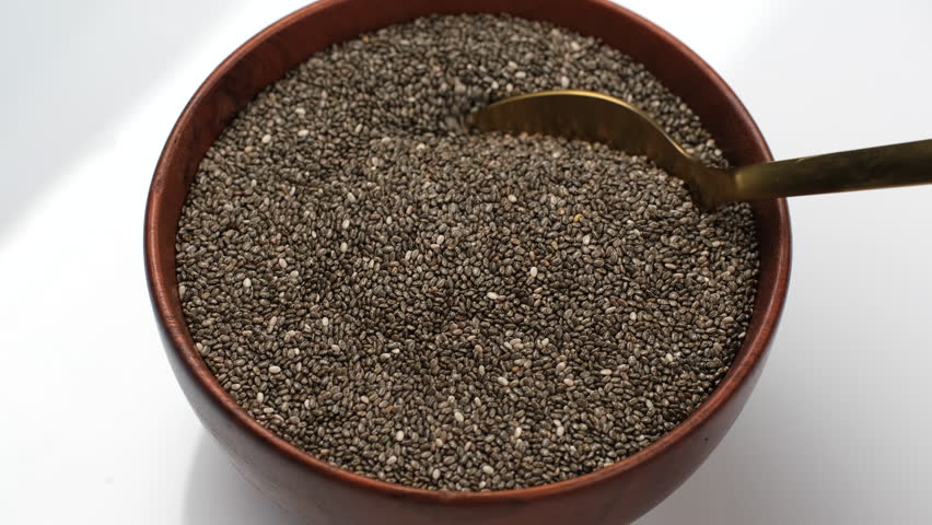 Scoop with spoon dry chia seeds from bowl. Cooking healthy vegan snack