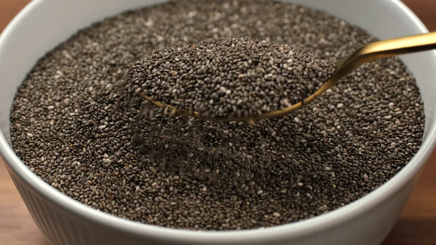Chia seeds healthy antioxidant food. Scoop with spoon dry chia seeds from bowl, close up