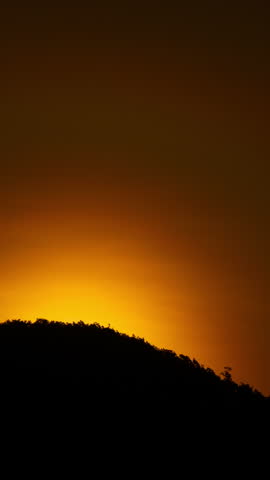 Timelapse of dramatic sunrise with orange sky in a cloudy day.