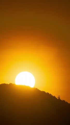 Timelapse of dramatic sunrise with orange sky in a cloudy day.