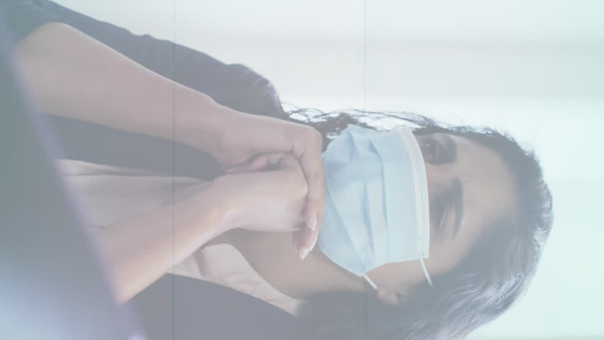 Stop sign over covid-19 cells moving against thoughtful woman wearing face mask at office. coronavirus covid-19 pandemic concept