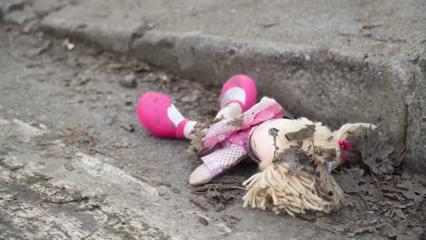 blonde rag doll dressed in pink abandoned on the side of the road in the middle of the dust