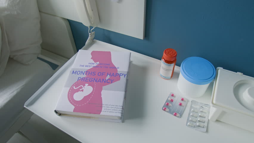 High angel shot book called months of happy pregnancy and pills on white nightstand near hospital bed