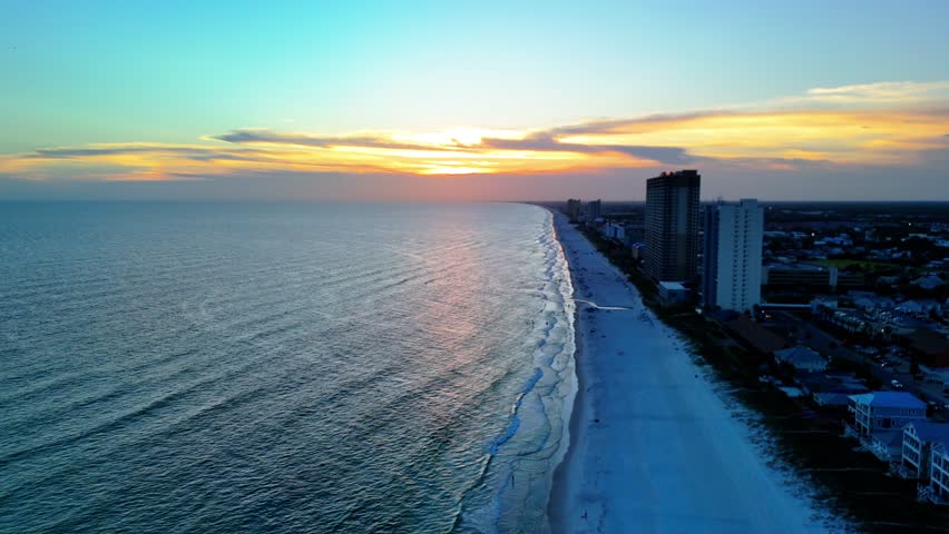 Aerial drone footage of a vibrant sunset over Panama City Beach, Florida, with sweeping shoreline views, ocean waves, and colorful skies. Perfect for travel, tourism, and coastal landscape projects.