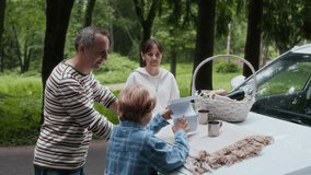 Father and son unfolding paper map on car hood and discussing their location while standing on country road in natural environment during family trip on summer weekend - Powered by Shutterstock - Get 15% off with code: PIKWIZARD15