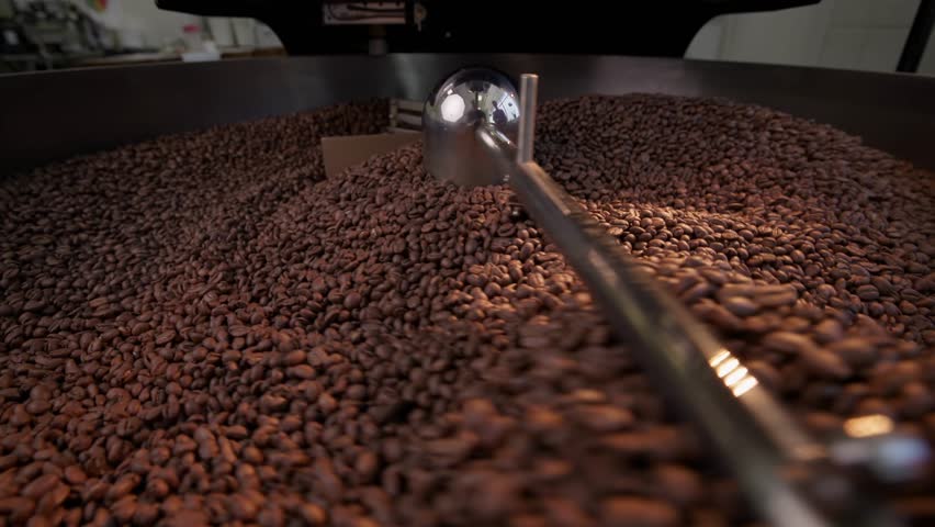 Artisan coffee roasting process featuring rotating beans in industrial roaster.