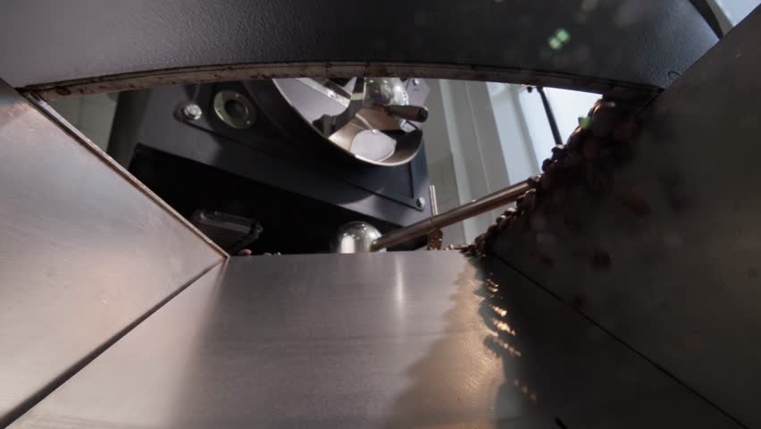 Dynamic coffee roasting process, beans pouring, tumbling, and cooling in industrial roaster machine in industry factory.