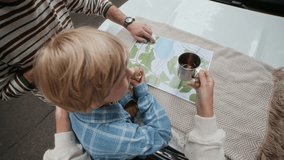 Tilt up and down of active family of father, mother and son standing by car hook, having tea and discussing their location and further route on paper map - Powered by Shutterstock - Get 15% off with code: PIKWIZARD15