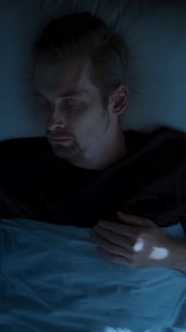 Top view, man restlessly sleeping in bed at night and waking up abruptly with a startle. Insomnia sleep paralysis, sleep disorder. vertical video