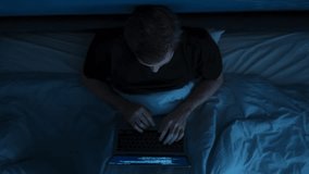 Overhead view of man using laptop for work in bed during late night hours. Programmer writing code in bed at night. Remote work, overwork or insomnia concept - Powered by Shutterstock - Get 15% off with code: PIKWIZARD15