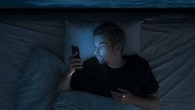 Time lapse, top view, a man uses his smartphone for a long time at night, scrolling through feeds and hanging out on social media instead of sleeping. Digital addiction - Powered by Shutterstock - Get 15% off with code: PIKWIZARD15