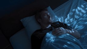 A young man wakes up tense and exhausted in bed at night, suffering from insomnia and a sleep disorder, covering his face with his hand. Sleep paralysis or nightmares - Powered by Shutterstock - Get 15% off with code: PIKWIZARD15