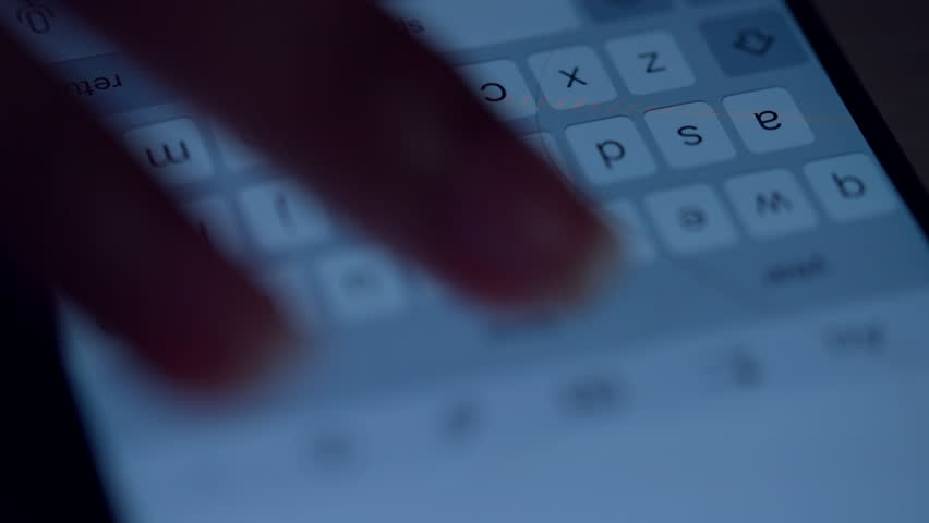 A hand is pressing the keys on a cell phone. The phone is displaying the letters "z" and "x"