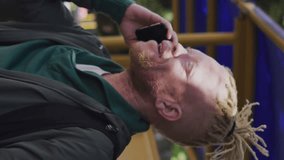 Animation of social media icons against african american albino man using smartphone. Social media networking and business technology concept - Powered by Shutterstock - Get 15% off with code: PIKWIZARD15