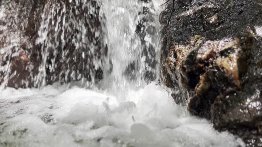 Mini Waterfall Falls on Black Rock with Flowing White Foam