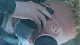 Animation of social media icons over albino man with face mask using smartphone. Global covid 19 pandemic, social media, and digital interface concept digitally generated video. - Powered by Shutterstock - Get 15% off with code: PIKWIZARD15