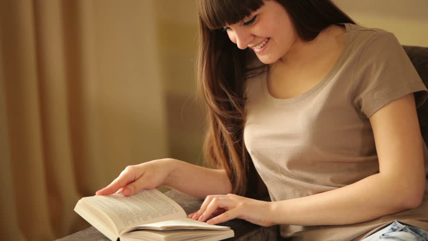 Young girl reading a book and smiling
