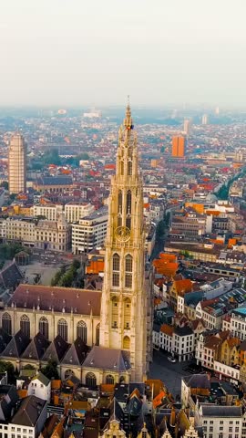 Vertical video. Antwerp, Belgium. Spire with the clock of the Cathedral of Our Lady (Antwerp). Historical center of Antwerp. City is located on river Scheldt (Escaut). Summer morning, Aerial View. Ri