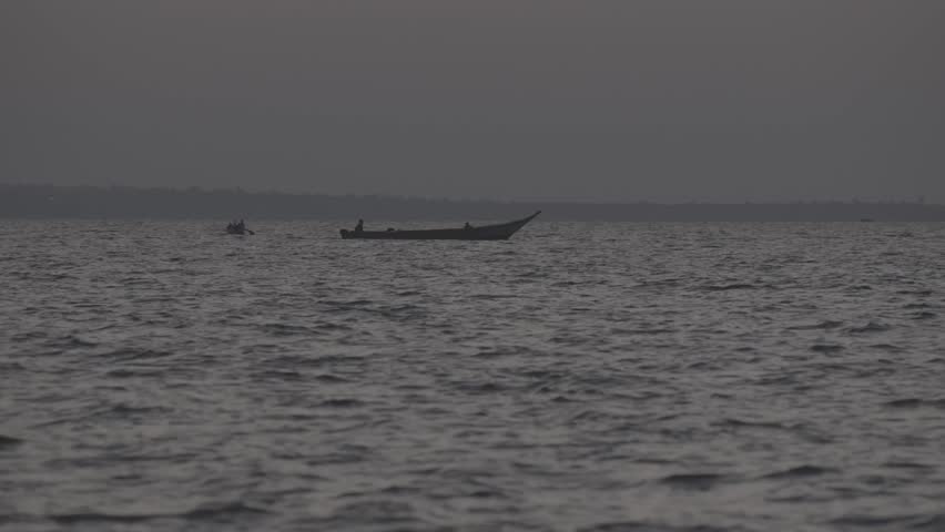 A silhouetted fisherman on a canoe before dawn on Lake Voctoria.