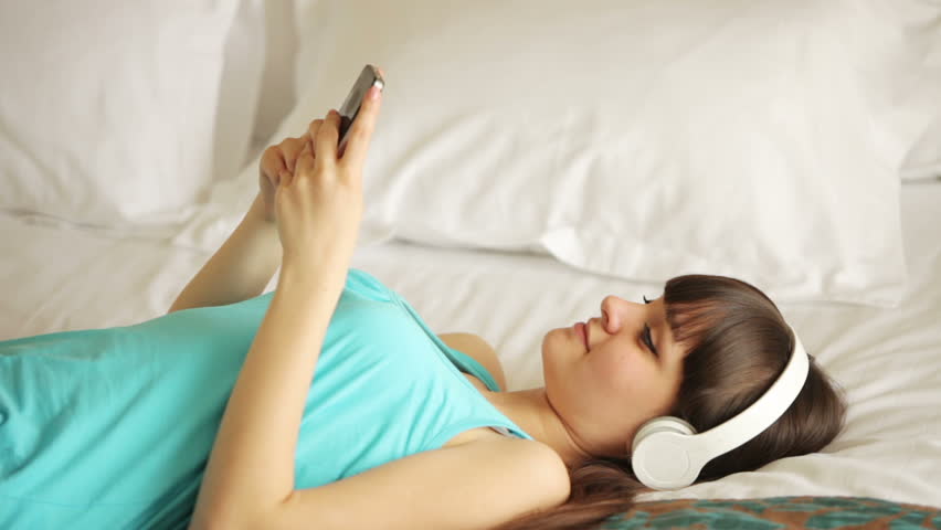 Young woman listening music on bed
