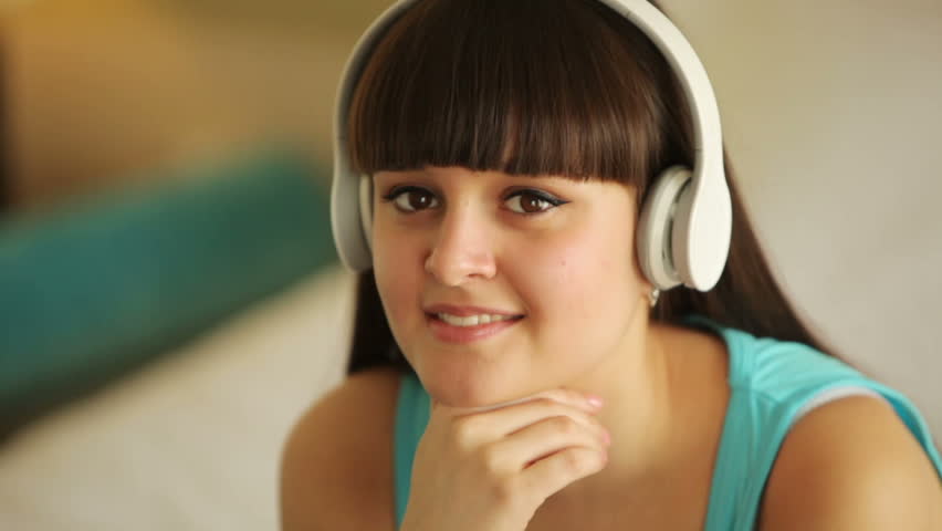 Young girl with headphones smiling at camera
