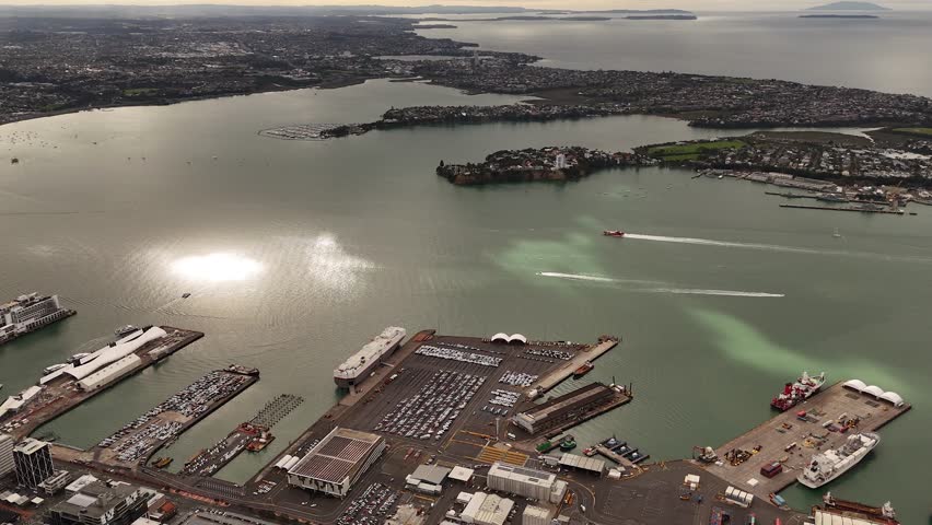 4K 60fps drone shot of passenger ferries arriving at the Downtown Ferry Terminal in Auckland, NZ. Captures the daily commute and bustling activity on the Waitematā Harbour with the city as a backdrop