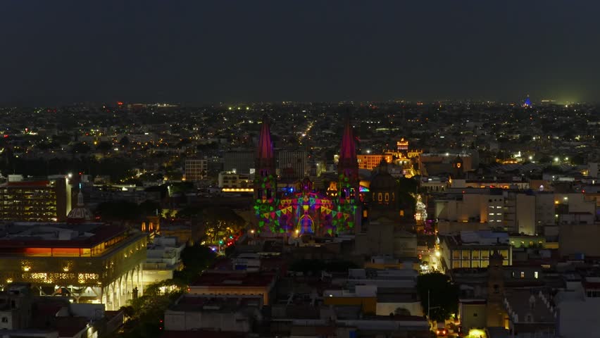 Catedral de Guadalajara illuminated by vibrant light projections celebrating Jalisco traditions and cultural icons at Aluzinante light sow. Dolly in nighttime aerial