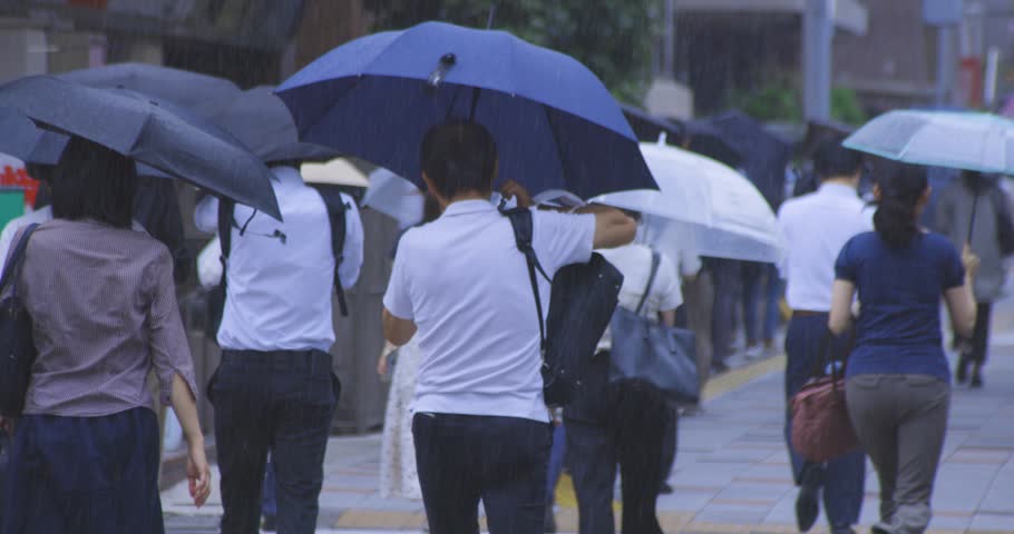 A slow motion of walking commuters on the city street in Tokyo rainy day telephoto