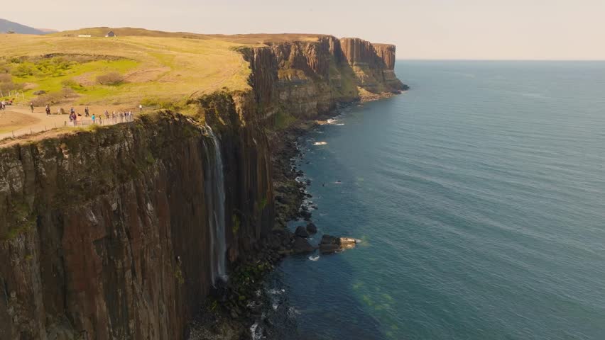 Aerial drone footage of Mealt Falls cascading from dramatic cliffs into the sea on the Isle of Skye, Scotland.