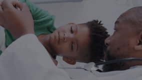 Animation of heart monitor over african american male doctor with boy patient. Global medicine, healthcare, digital interface, computing and data processing concept digitally generated video. - Powered by Shutterstock - Get 15% off with code: PIKWIZARD15