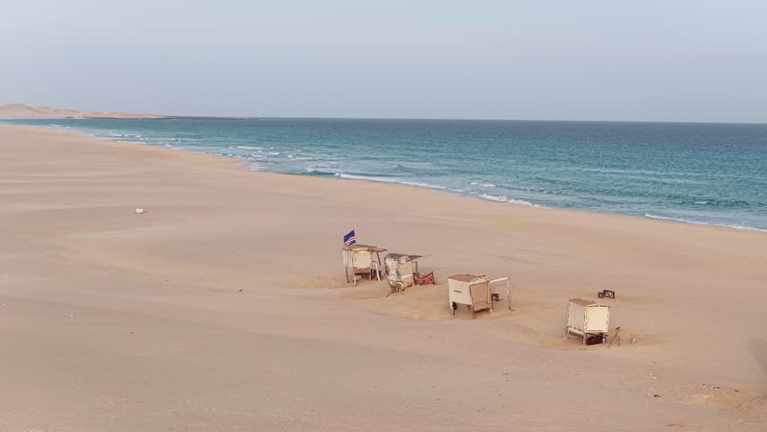 Praia de Chaves ( Chaves beach),Ocean,sandy dune and wooden shops on the beach with the Cape Verdean flag flying.Boa Vista island situated in the Atlantic Ocean.Cabo Verde, Africa.