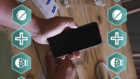 Animation of medical covid 19 icons over senior man using smartphone at home. global covid 19 pandemic, health and medicine concept digitally generated video. - Powered by Shutterstock - Get 15% off with code: PIKWIZARD15