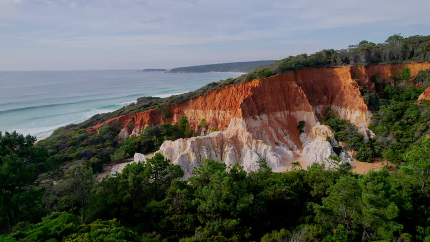 Aerial view of The Pinnacle in Beowa National Park, New South Wales. Striking orange and white rock formation captured by drone in soft ligh