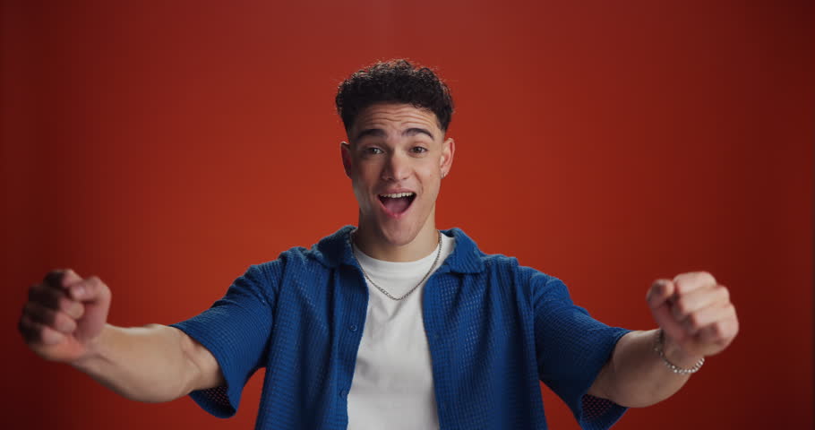 Face, man and excited with celebration in studio for competition winner, bonus and giveaway prize. Surprise, person and victory fist on red background for contest champion, achievement and milestone