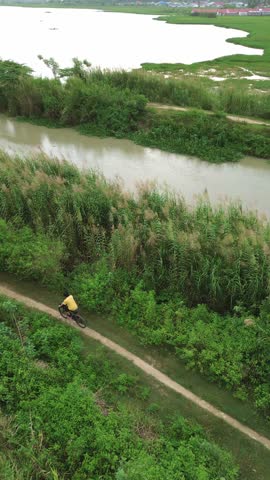 Aerial View of Cyclist Riding Along River Path