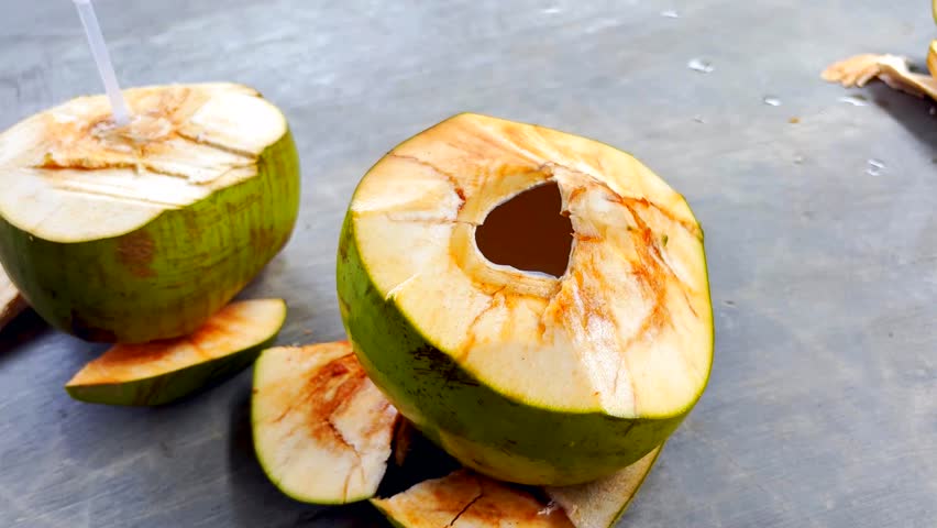 Fresh young coconut served for drinking. Closeup of a woman hand taking an open coconut to drink the water.