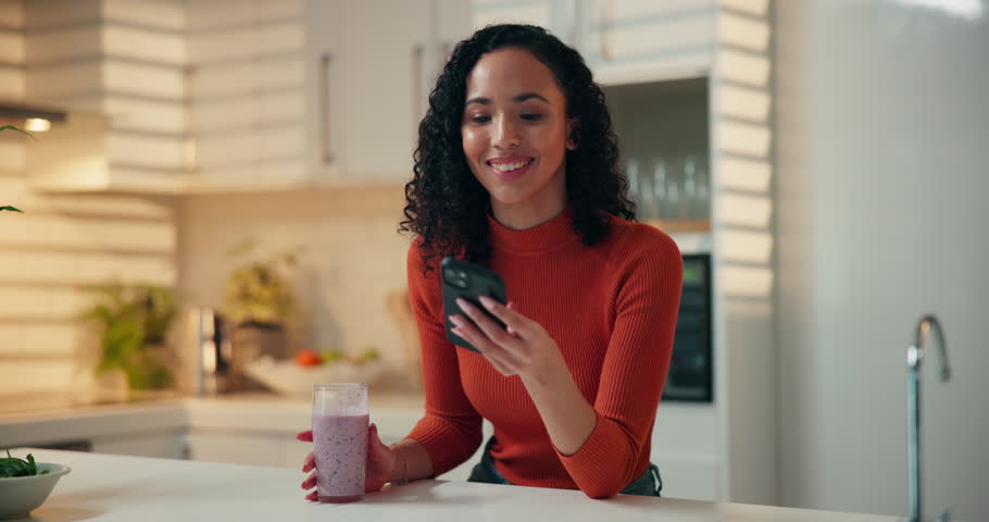 Happy, woman and smoothie with phone in kitchen for breakfast shake, nutrition and reading text. Home, person and smartphone with meal replacement drink for healthy benefits and social media scroll